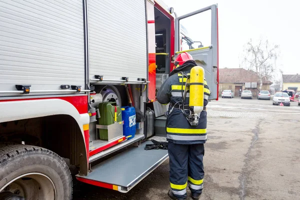 Firefighter is helping fellow to assembly his gear, keep balance and direction, checking equipment.