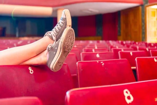 Long exposure photo, young woman posing with crossed legs in empty theater.
