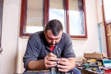 Heykeltraş duruş, metal tel atölyesini yapılmış figürleri tutum veriyor.