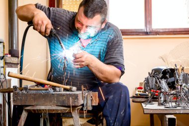 Heykeltraş uygun koruma, silâhsız olmadan derleme metal heykel için ark kaynağı kullanıyor.