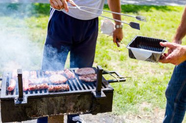 Adam kavrulmuş Kebap metal maşa ile al, onları plastik kabın içine Barbekü kaldırır. 
