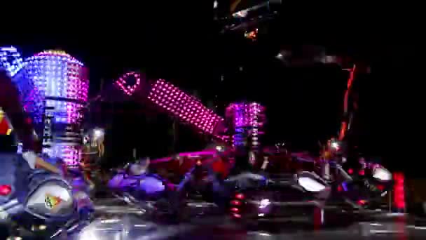夜の遊園地でカラフルな糸車 高速夜ルナ公園の鮮やかな電光に照らされてカラフルなカルーセルを回転 — ストック動画