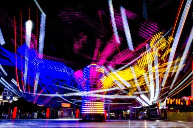 Uzun pozlama canlı aydınlatmalar ile gece ışıklı bir hızlı dönen renkli atlıkarınca, lunapark sürmek Luna parkta.