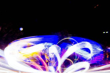 Uzun pozlama canlı aydınlatmalar ile gece ışıklı bir hızlı dönen renkli atlıkarınca, lunapark sürmek Luna parkta.