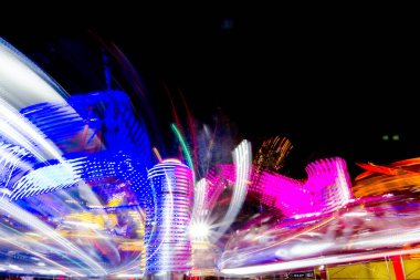 Uzun pozlama canlı aydınlatmalar ile gece ışıklı bir hızlı dönen renkli atlıkarınca, lunapark sürmek Luna parkta.