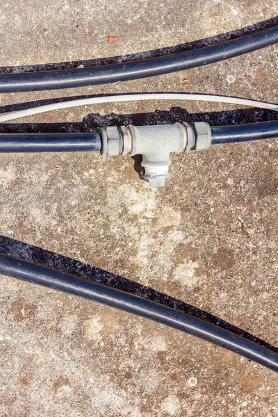 Wenige Schwarze Kunststoff Wasserschläuche Mit Verzweigung Werden Auf Betonboden Gelegt — Stockfoto