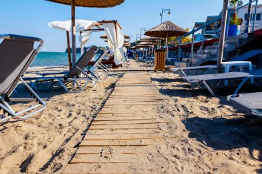 Ahşap yolu, kumlu boş Halk Plajı, şemsiye ve şezlonglar için mükemmel bir tatil geçiyor.