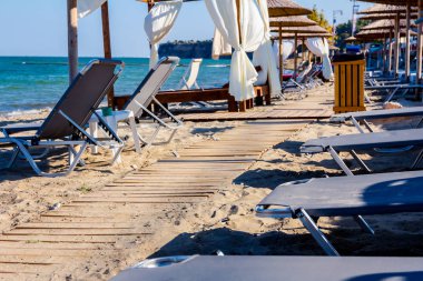 Ahşap yolu, kumlu boş Halk Plajı, şemsiye ve şezlonglar için mükemmel bir tatil geçiyor.