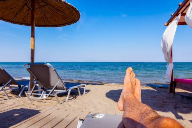 Adamın bacakları kadar tembel kıyı şeridi, Halk Plajı yanında kaygısız yalan söyleyerek güneş banyosu.