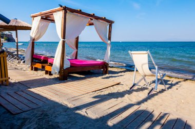 Lüks rahat ahşap pergola şemsiye için beyaz perde ile güneşli kumsalda yerleştirilir.
