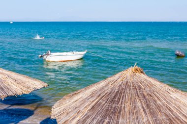 Boş Halk Plajı ile thatched şemsiye, şemsiye ve şezlonglar kumlu kıyı şeridi boyunca görüntüleyin. Küçük iskele tekne sahile yakın bağlantılı.
