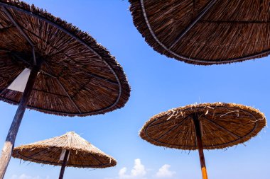 Üzerinden vurdu thatched plaj şemsiyesi altındaki mavi gökyüzü üzerinde. Ve reed ile