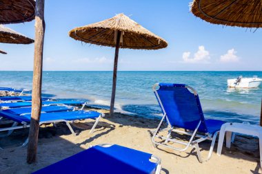 Boş Halk Plajı ile thatched şemsiye, şemsiye ve şezlonglar kumlu kıyı şeridi boyunca görüntüleyin. Küçük iskele tekne sahile yakın bağlantılı.