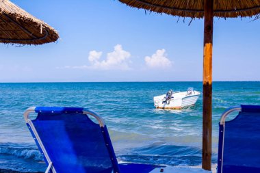 Boş Halk Plajı ile thatched şemsiye, şemsiye ve şezlonglar kumlu kıyı şeridi boyunca görüntüleyin. Küçük iskele tekne sahile yakın bağlantılı.