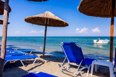 Boş Halk Plajı ile thatched şemsiye, şemsiye ve şezlonglar kumlu kıyı şeridi boyunca görüntüleyin. Küçük iskele tekne sahile yakın bağlantılı.