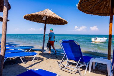 Boş Halk Plajı ile thatched şemsiye, şemsiye ve şezlonglar kumlu kıyı şeridi boyunca görüntüleyin. Küçük iskele tekne sahile yakın bağlantılı.