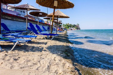 Boş Halk Plajı ile thatched şemsiye, şemsiye ve şezlonglar kumlu kıyı şeridi boyunca görüntüleyin.