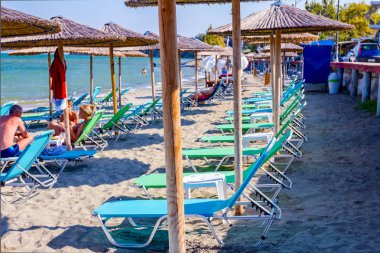 Boş Halk Plajı ile thatched şemsiye, şemsiye ve şezlonglar için mükemmel bir tatil görüntüleyin.