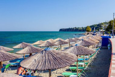 Geçit arkasında, Halk Plajı üzerinde şemsiye, şemsiye ve şezlonglar insanlar, kıyı şeridi yanındaki yer turist ile thatched.