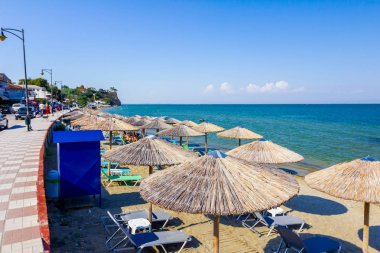 Geçit arkasında, Halk Plajı üzerinde şemsiye, şemsiye ve şezlonglar insanlar, kıyı şeridi yanındaki yer turist ile thatched.