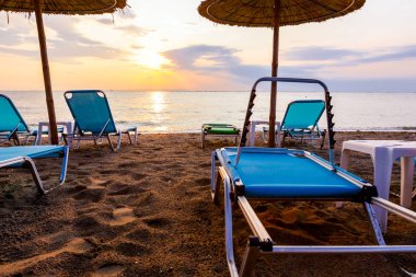 Erken sabah güneş, şafak, Halk Plajı ile thatched şemsiye, şemsiye ve şezlonglar deniz kıyı şeridi boyunca görüntüleyin.