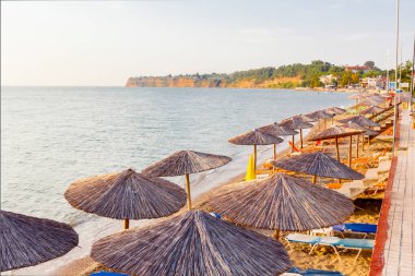 Geçit arkasında, boş Halk Plajı ile thatched şemsiye ve şezlonglar erken sabah güneş üzerindedir.
