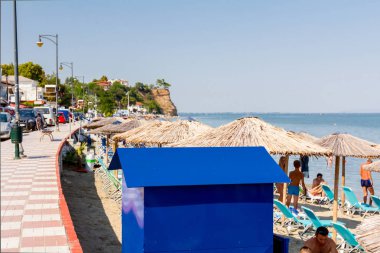 Mavi metal aşınma değişen kabin thatched şemsiye, şemsiye ve şezlonglar ile kum plajındaki turist yanındaki sahil şeridi vardır..