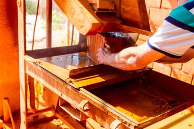 İşçi kırmızı tuğladan temiz kesim yapmak için elektrikli alet kullanıyor. Testere yüksek hızda döndüğü için malzemeyi kesmek için aşındırıcı bir etki kullanıyor..