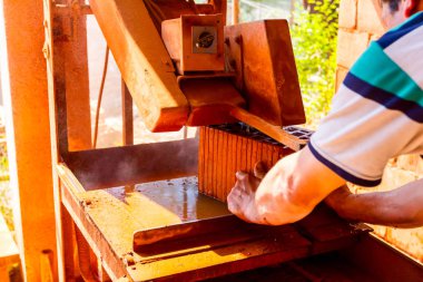 İşçi kırmızı tuğladan temiz kesim yapmak için elektrikli alet kullanıyor. Testere yüksek hızda döndüğü için malzemeyi kesmek için aşındırıcı bir etki kullanıyor..