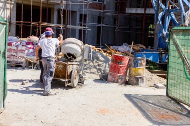 İşçiler taşıması için vinç kancalarına bağlı el arabalarına havan topu dökerler..