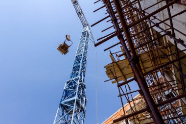 Crane el arabası taşıyor, inşaat alanının yukarısındaki halatlara çekiliyor..
