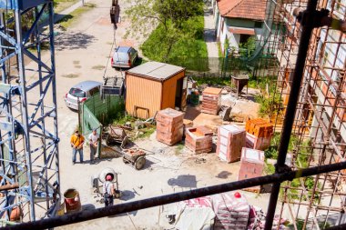 Crane el arabası taşıyor, inşaat alanının yukarısındaki halatlara çekiliyor..