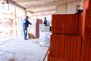 Arka planda çalışan yılında kırmızı blok yığını el ile teslim palet plastik folyo Paketli için forklift kullanıyor.