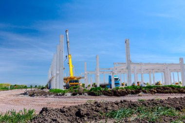 Vinçler-Mobil vinç montaj endüstriyel bina büyük beton iskelet var. Manzara dönüşümü makine ile kentsel alan kişi çalışıyor. Şantiye görüntülemek.