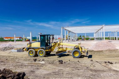 Santral sarı çizgili araç kullanıyor. İnşaat alanındaki zemini düzleştiriyor..