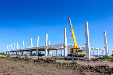 Vinçler-Mobil vinç montaj endüstriyel bina büyük beton iskelet var. Manzara dönüşümü makine ile kentsel alan kişi çalışıyor. Şantiye görüntülemek.
