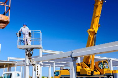 Rigger yüksek kiraz toplayıcıda. İnşaat alanının üzerinden geçiyor..