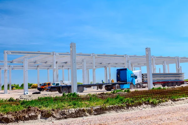 トレーラーとトラック輸送産業用建物の建設現場に長くて重いコンクリート梁 — ストック写真