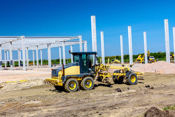 Operator is driving yellow grader, leveling ground at building site.