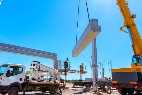 アセンブリの巨大な建設のためのコンクリートの梁を管理する移動式クレーンを支援している労働者 — ストック写真