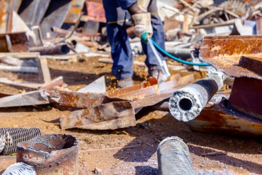 İşçi oksijen ve asetilen ve propan karıştırarak atık metali gazla kesiyor..