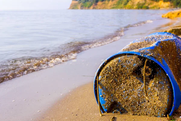 Used blue plastic drums for storing water and other liquids is washed up by the sea on sandy beach, waste.