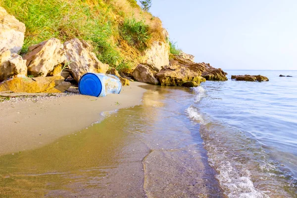 Used blue plastic drums for storing water and other liquids is washed up by the sea on sandy beach, waste.