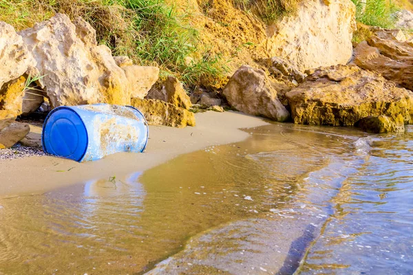 Used blue plastic drums for storing water and other liquids is washed up by the sea on sandy beach, waste.