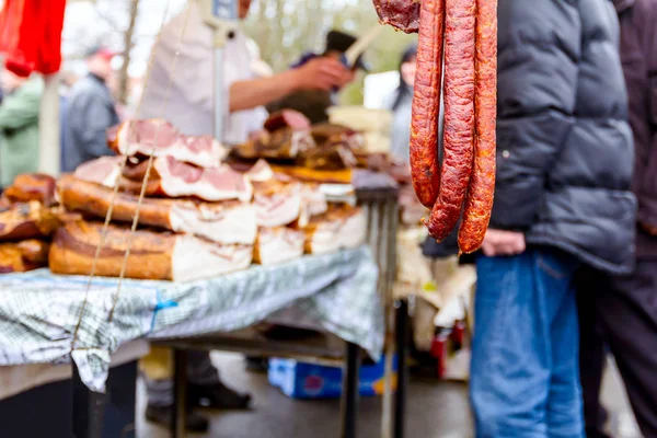 Cured meat and sausages hang for sale at outdoor flea market.