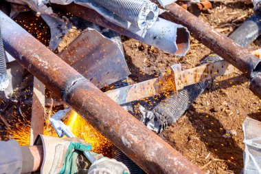 İşçi oksijen ve asetilen ve propan karıştırarak atık metali gazla kesiyor..