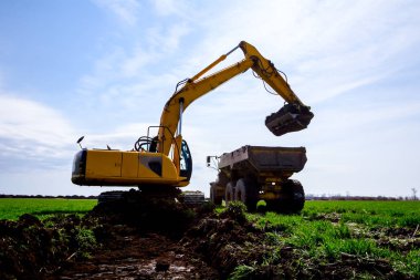 Ekskavatör bina site üzerinde zemin ile bir kamyon yükleniyor