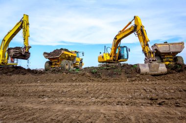 Büyük ekskavatörler bina üzerinde zemin ile iki kamyon yükleniyor si