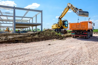 Backhoe şantiyede zemin ile bir kamyon yükleniyor