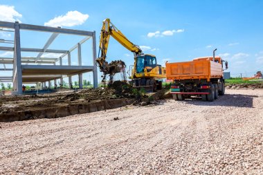 Backhoe şantiyede zemin ile bir kamyon yükleniyor